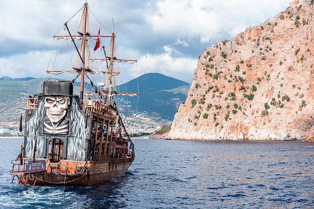 pirate ship sailing near rocky cliff