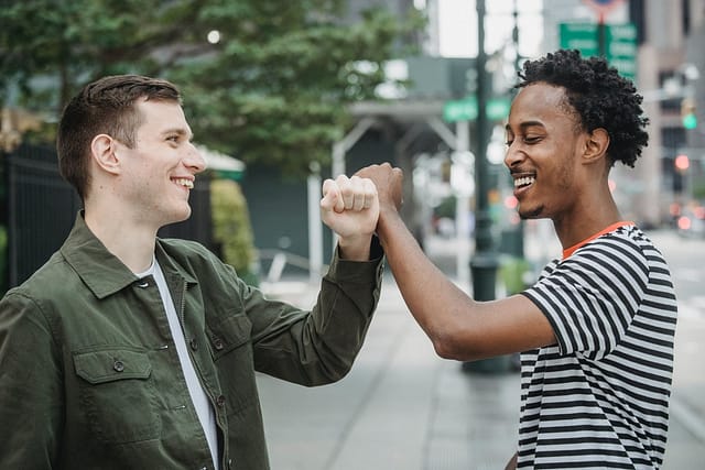 positive young multiethnic friends greeting each other on street